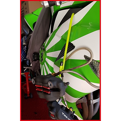 Motorrad in Grün und Weiß mit Sonnensymbol. Bremsen und gelbe Stange im Fokus.